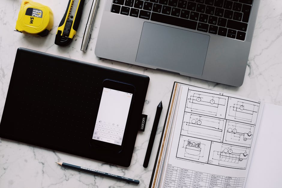From above view of modern workplace at white marble table with various gadgets and tools and opened notebook with drawings with pen and pencil
