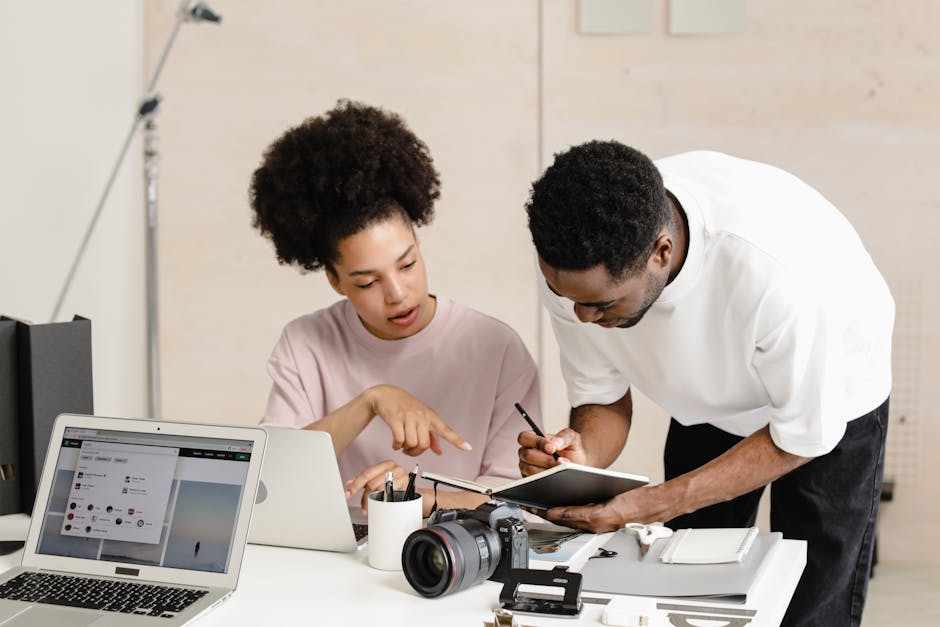 Two coworkers engaged in a project at a modern desk with digital tools.